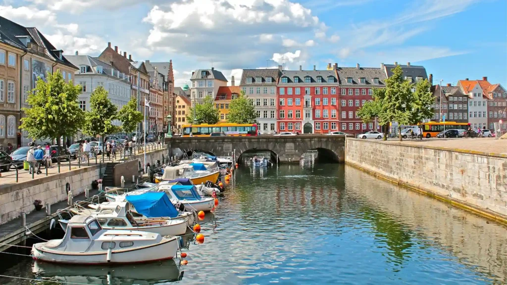 a canal with boats and buildings in the background and the place is Copenhagen