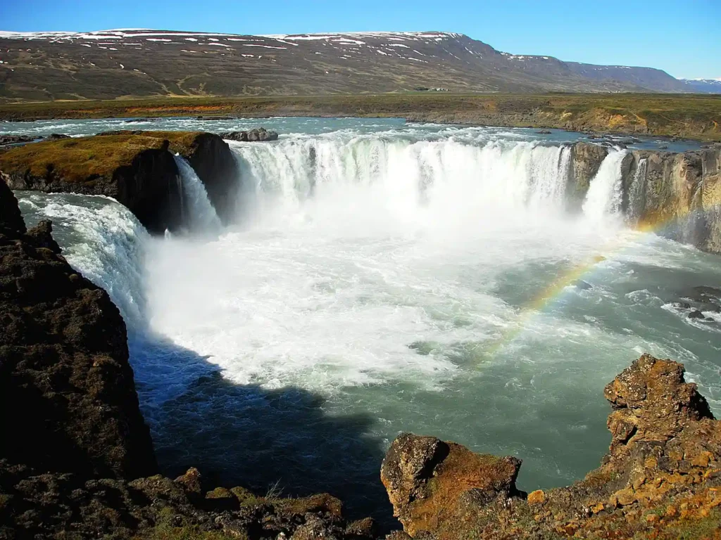 a waterfall with a rainbow in the background