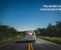 A nighttime road trip scene with a white van driving on a two-lane road surrounded by lush greenery. The sky is clear, and there are a few stars visible. The text "Why Shouldn't You Start a Road Trip Late in the Night?" is placed at the top right corner of the image.